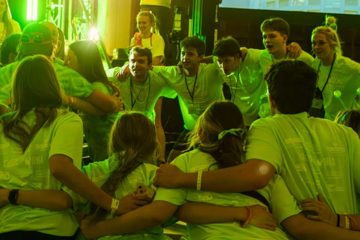 students in green tshirts huddling together