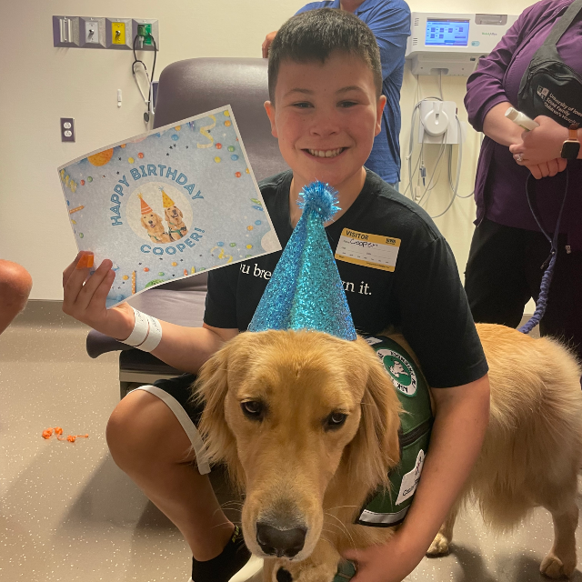 cooper and facility dog Nacho with a happy birthday certificate and hat